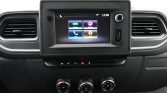 Car dashboard with a central touchscreen display showing app icons, flanked by air vents and control buttons.