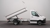 White tipping dump truck shown from the side with its cargo bed raised, ready to unload material.