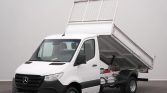 White Mercedes cargo truck with the dump bed raised for unloading and a black bumper.