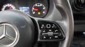Close-up of a car steering wheel (Mercedes) showing right-hand control cluster with volume, phone, and star buttons.