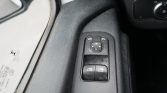 Close-up of a car's driver-side door control panel with window switches and a circular mirror adjustment joystick.