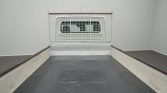 Empty truck bed with white walls and a metal mesh guard at the far end of the cargo area.