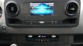 Car dashboard center with a touchscreen infotainment display between two circular air vents and control buttons beneath it.