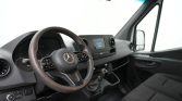Interior view of a Mercedes-Benz van cockpit with steering wheel, center touchscreen, gear shifter, and front seats