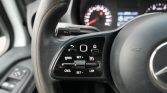 Close-up of left-side steering wheel with cruise control buttons (RES, SET, CNCL, LIM) and stalk, dashboard blurred behind.