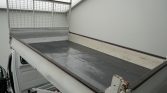 Flatbed truck cargo area with a metal mesh partition at the cab end, empty and ready for loading