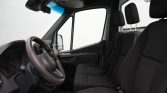 Interior view of a vehicle cabin showing the steering wheel and three front seats, with a large windshield and dashboard.
