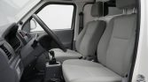 Interior of a gray commercial van cockpit with steering wheel, gear shifter, and two front seats viewed from the open door