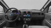 Interior view of a car cockpit: steering wheel, central touchscreen infotainment, climate controls, and gear shift between two front seats.
