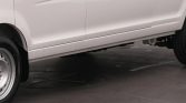 Side view of a white van showing the lower rocker panel and exposed undercarriage near the ground on pavement