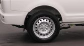 Rear wheel of a white van with a steel rim and black tire on a paved surface in a parking lot