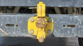 Close-up of a yellow trailer hitch with a rusted ball on a dark metal frame, ready to connect a trailer to a vehicle.