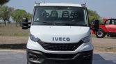 Front view of a white Iveco truck parked on a paved lot with trees in the background.