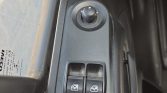 Close-up of a car door control panel with two power window switches and a round mirror adjustment dial