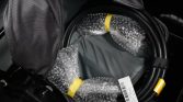 Coiled black cable with yellow ends in a bag, wrapped in bubble wrap and a white shipping tag attached.