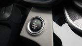 Push-to-start engine button with a green indicator on a car's center console area.