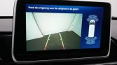 In-car rearview camera display showing parking guidance lines (red, yellow, green) and a top-down car with sensor rings on the right side.