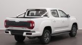 Rear three-quarter view of a white Maxus T90 EV pickup with a bed sport bar and tailgate branding visible (Maxus logo on tailgate).