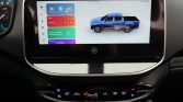 Car dashboard touchscreen displaying a blue pickup truck graphic with colorful app tiles beside it.