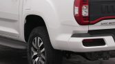 Rear right side of a white pickup truck showing the taillight, bumper and rear wheel.