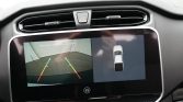 Car dash touchscreen showing rearview camera with colored guide lines and a top-down parking aid on the right