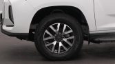 Front left wheel of a white SUV, showing a black tire and multi‑spoke alloy rim.