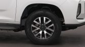 Front left wheel of a white SUV with a rugged alloy rim and tire visible under the fender