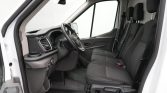 Front cabin of a white van with the driver’s seat, two passenger seats, steering wheel, and dashboard visible near the door