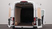 White cargo van with all rear doors open, showing an empty cargo space lined with plywood panels and a coiled blue hose on the floor.