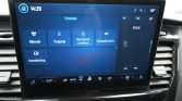 Car infotainment touchscreen showing 'Functies' with tiles: Rijmodi, Toegang, Vertrek en comfort, Opladinstelling, Handleiding; time 14:29, 18°C, FM 87.60