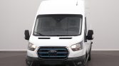 Front view of a white Ford cargo van with a bold grille and blue-accented bars, headlights on, against a neutral backdrop.