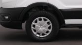Close-up of a white van's front wheel and tire, showing a black fender and bumper area.