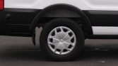 White van with black trim showing a single wheel and tire, hubcap visible in the wheel well.