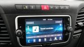 Car infotainment touchscreen in a vehicle displaying 'Toestel aansluiten' (connect device) with media controls beneath the screen