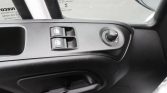 Door panel in a car showing two window switches and a circular mirror adjustment knob, with the interior door handle below.