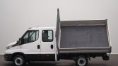 White dump truck with its metal cargo bed raised, ready to unload on a paved surface, side view