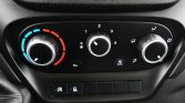 Car climate control panel: left temperature dial set to cool with blue-to-red gradient, center fan speed at 1, right dial directs airflow to face and feet; A/C button lit; recirculation button nearby.