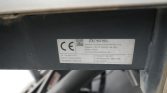 Close-up of a dark metal frame with a CE certification label showing manufacturer details and product specifications, including dimensions and serial number.