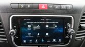 Car dashboard with a center touchscreen infotainment system showing apps (Back-up camera, Compass, Radio, Vehicle, Audio settings, Settings).