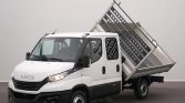 White Iveco light truck with a tilted metal tipping bed in a studio setting.