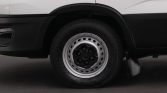 Close-up of a van's wheel: black hub with silver steel rim, tire, and wheel arch on a two-tone white and black vehicle
