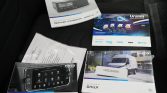 Set of Iveco product manuals and brochures laid on a dark car seat, including a Daily infotainment unit cover image and vehicle graphics.