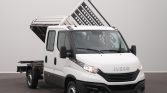 White Iveco dump truck with its tilting cargo bed raised, parked indoors on a gray background.
