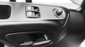 Driver's door panel with two power window switches and a round mirror adjustment joystick, plus the door handle nearby
