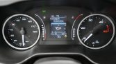 Car dashboard instrument cluster with a large speedometer on the left, tachometer on the right, and a central digital display showing engine information and trip data.