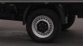 Close-up of a silver steel wheel and black tire on a cargo truck, undercarriage visible above.