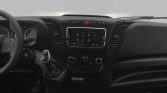 Interior of a vehicle cabin featuring a steering wheel, gear shifter, and a central touchscreen infotainment system with climate controls below it.