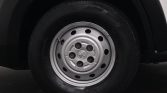 Close-up of a car wheel with a silver steel rim and five lug nuts on a black tire
