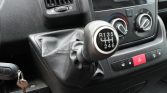 Manual gear shift knob beside climate control dials and hazard button in a vehicle interior
