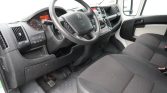 Interior of a van cockpit showing steering wheel, dashboard and front seats from the driver’s side